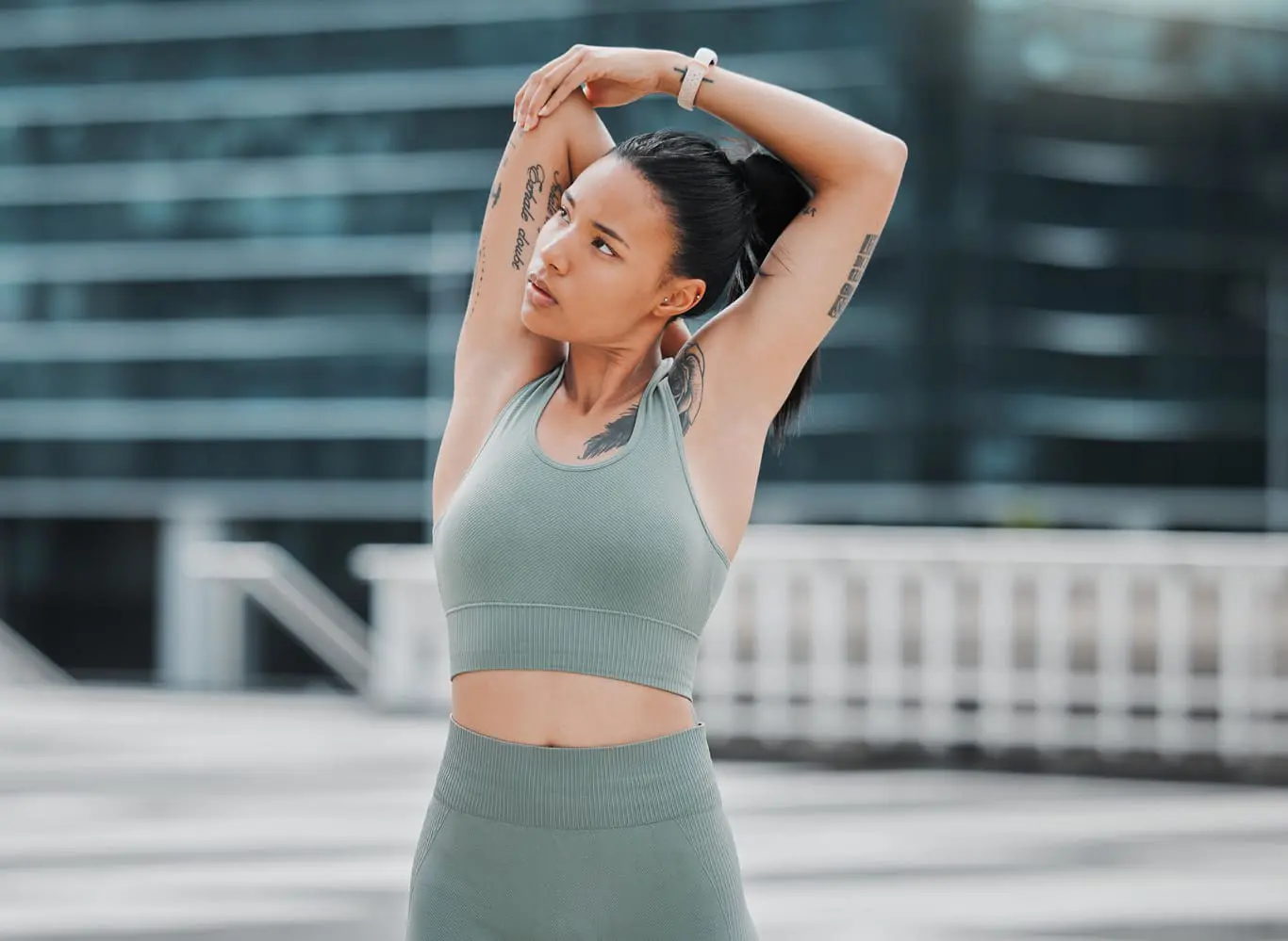 Mixed race female athlete stretching her arms by touching her back outside before exercising. Runner focused on her fitness and cardio health stretching her arm before starting her jog in the city Brachioplasty in Charleston County, SC