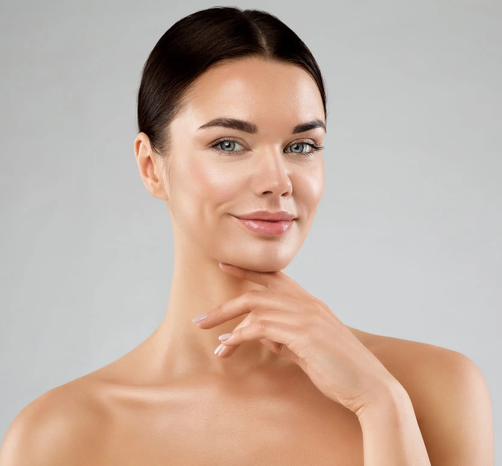 Beauty Model with Smooth Skin touching Chin. Happy Young Woman with Perfect Face Make up over White. Women Facial Spa Cosmetics and Anti Age Cosmetology. Female Plastic Surgery Facelift in Charleston County, SC